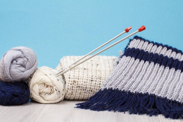 Wollen trui, sjaal en garen voor het breien. strengen van natuurlijke wol en breinaalden - Foto, afbeelding