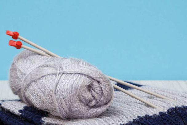 Woolen scarf and yarn for knitting. Skeins of natural wool yarn and knitting needles - 写真・画像