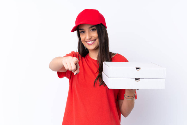Kobieta dostarczająca pizzę trzyma pizzę nad odizolowaną białą ścianą wskazuje palcem na ciebie z pewnym wyrażeniem - Zdjęcie, obraz
