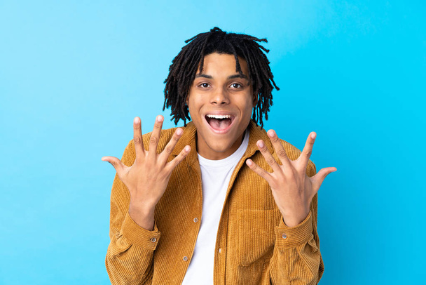 Young African American man with corduroy jacket over isolated blue background with surprise facial expression - Photo, Image