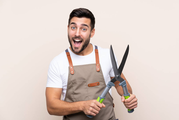 Gardener man holding a pruning shears over isolated background - Photo, Image
