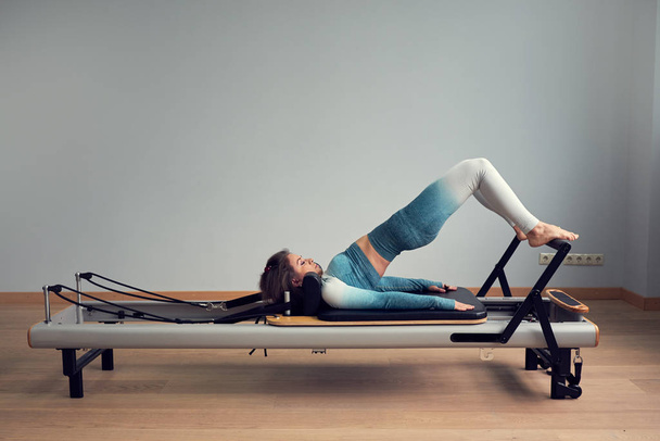 leotard workout pilates training. athletic pilates reformer exercises. pilates machine equipment. young asian woman pilates stretching sport in reformer bed instructor girl in a studio - Valokuva, kuva