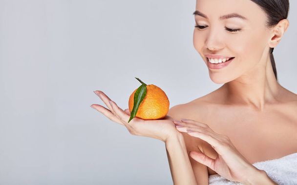 Close-up, a beautiful young Asian model smiles with citrus in her hand. - Foto, Imagem