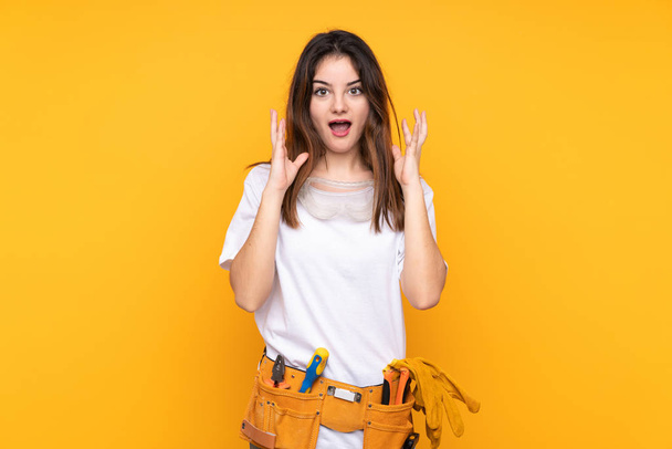 Mujer electricista joven sobre aislado sobre fondo amarillo con expresión facial sorpresa - Foto, imagen