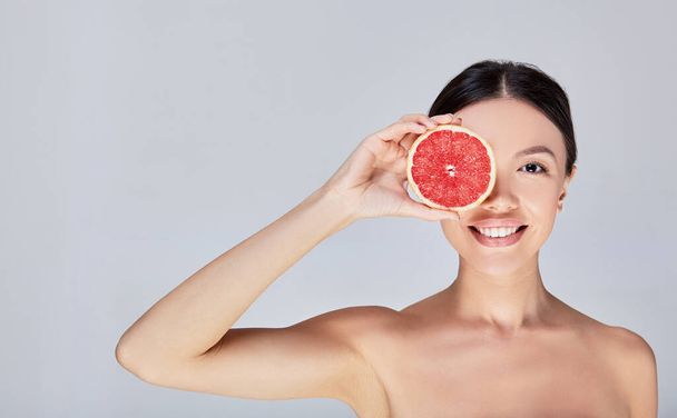 An image of a cute fun young model with citrus on her face. - Photo, Image