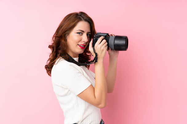Jeune femme russe sur fond rose isolé avec un appareil photo professionnel
 - Photo, image