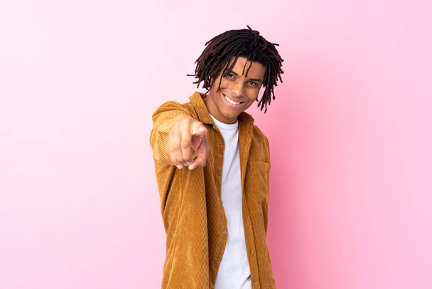 Jeune homme afro-américain avec veste en velours côtelé sur fond rose isolé pointe du doigt vers vous avec une expression confiante
 - Photo, image