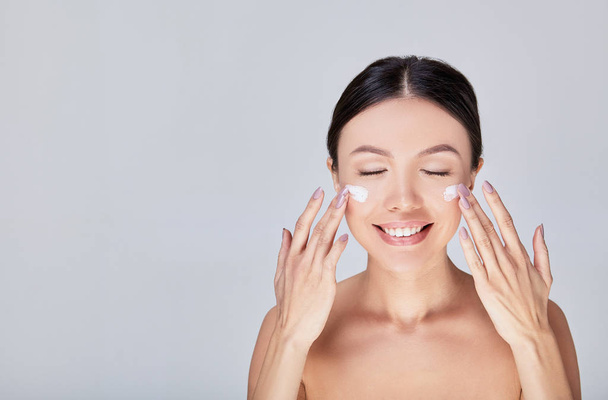 A cute Asian woman closing her eyes apply cream for her face. - Fotografie, Obrázek