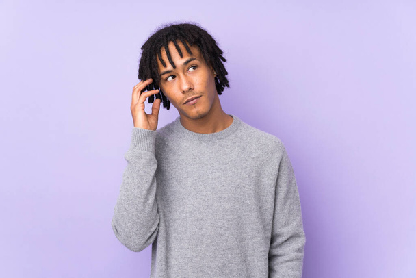 Молодий афроамериканець, ізольований на фіолетовому фоні, думає про ідею - Фото, зображення