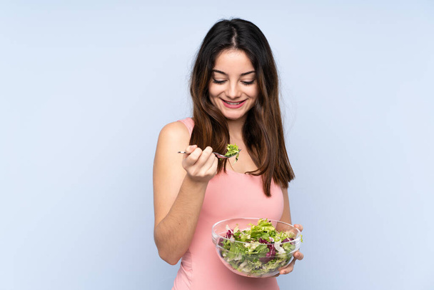 Mavi arka planda salata tutan beyaz bir kadın. - Fotoğraf, Görsel