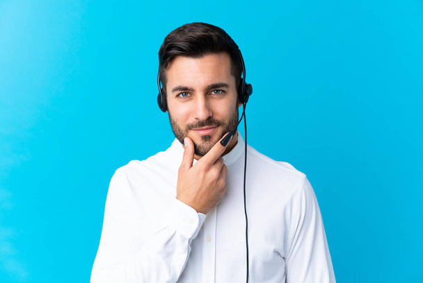 Uomo telemarketer che lavora con un auricolare su isolato sfondo blu ridendo
 - Foto, immagini