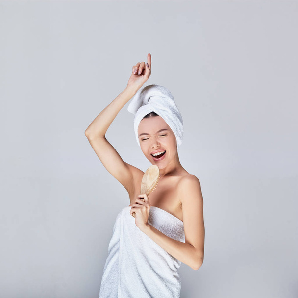 The cheerful Asian woman came out of the shower and sings against a gray background. - Foto, Imagen