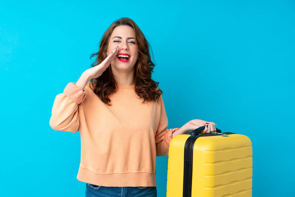 Utazó nő bőrönd felett elszigetelt kék háttér kiabál száj széles nyitott - Fotó, kép