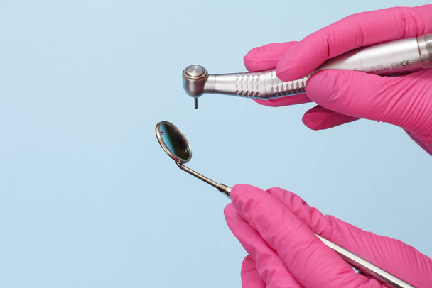 Χέρια οδοντίατρου σε γάντια με οδοντικό αντικείμενο και στοματικό καθρέφτη. - Φωτογραφία, εικόνα