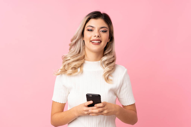 Teini tyttö yli eristetty vaaleanpunainen tausta lähettää viestin tai sähköpostia mobiili - Valokuva, kuva