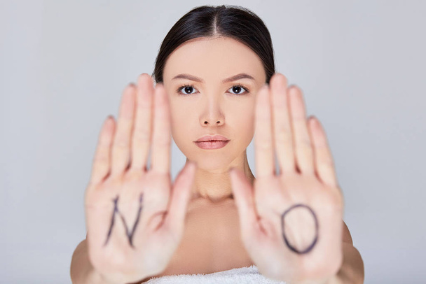 Mujer asiática joven y seria con la inscripción NO en sus palmas
. - Foto, imagen
