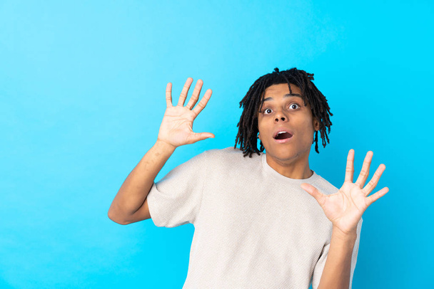 Молодой афроамериканец на изолированном синем фоне нервничает и боится
 - Фото, изображение