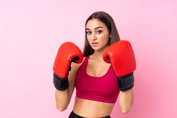 Юная спортсменка на изолированном розовом фоне в боксёрских перчатках - Фото, изображение