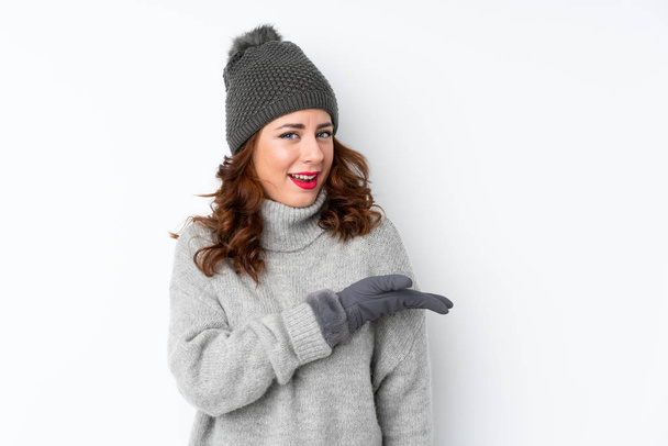 Young Russian woman with winter hat over isolated white background extending hands to the side for inviting to come - Foto, Imagen