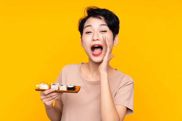 jong aziatisch meisje met sushi schreeuwen met mond wijd open - Foto, afbeelding
