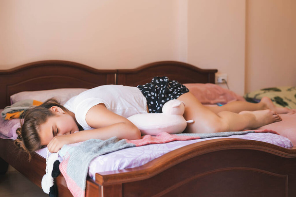 Retrato muito bonito adolescente menina na cama em apartamento moderno na parte da manhã. Menina adolescente bonito deitado e rindo em sua cama de pijama
 - Foto, Imagem