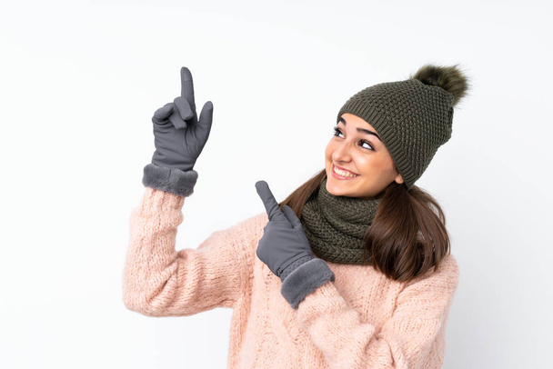 Młoda dziewczyna w czapce zimowej na białym tle wskazując palcem wskazującym świetny pomysł - Zdjęcie, obraz