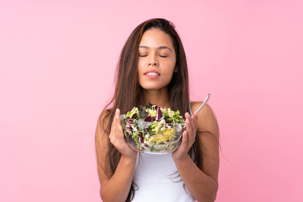 Joven brasileña con ensalada saludable sobre respaldo rosa aislado
 - Foto, Imagen