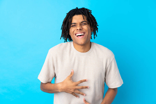 Νεαρός Αφροαμερικανός πάνω από απομονωμένο μπλε φόντο χαμογελώντας πολύ - Φωτογραφία, εικόνα