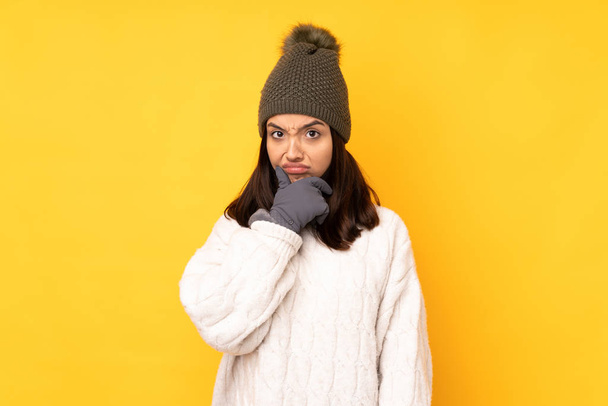 Молода жінка з зимовим капелюхом над ізольованим жовтим фоном мислення
 - Фото, зображення