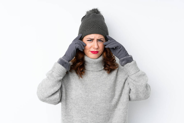 junge russische Frau mit Wintermütze über isoliertem weißem Hintergrund unglücklich und frustriert über etwas. negativer Gesichtsausdruck - Foto, Bild