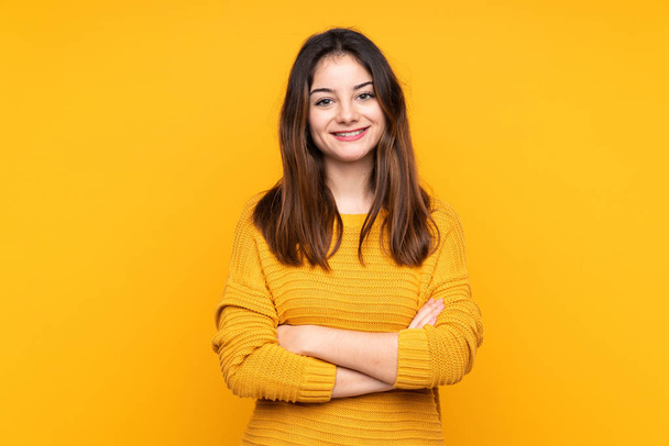 Young caucasian woman isolated on yellow background with arms crossed and looking forward - Fotó, kép