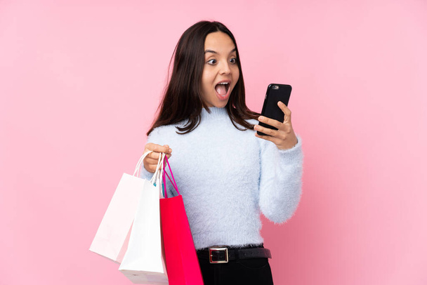 若いです女性とともにショッピングバッグ以上隔離されたピンクの背景保持コーヒーへ取り去ると携帯電話 - 写真・画像
