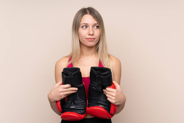 Young sport blonde woman over isolated background with boxing gloves - Photo, Image