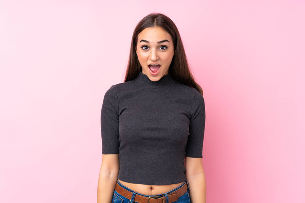 junges Mädchen über isoliertem rosa Hintergrund mit überraschendem Gesichtsausdruck - Foto, Bild