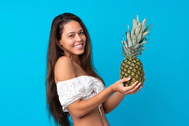fiatal nő a nyári szünetben ananász felett elszigetelt kék háttér - Fotó, kép