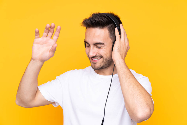 Молодой человек с жёлтым фоном слушает музыку и танцует
 - Фото, изображение