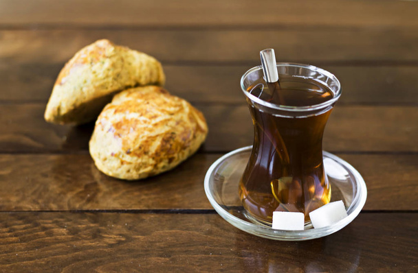 glass of Turkish tea and bread buns on wooden background - Fotoğraf, Görsel