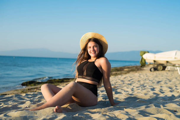 Fröhliches Plus-Size-Teenager-Mädchen mit Hut, das den Strand genießt. lächelnd, glücklich, positive Emotionen, sommerlicher Stil. - Foto, Bild