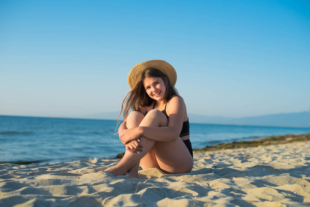 Wesoły plus rozmiar nastoletnia dziewczyna w kapeluszu korzystających z plaży. uśmiechnięta, szczęśliwa, pozytywna emocja, w stylu letnim. - Zdjęcie, obraz