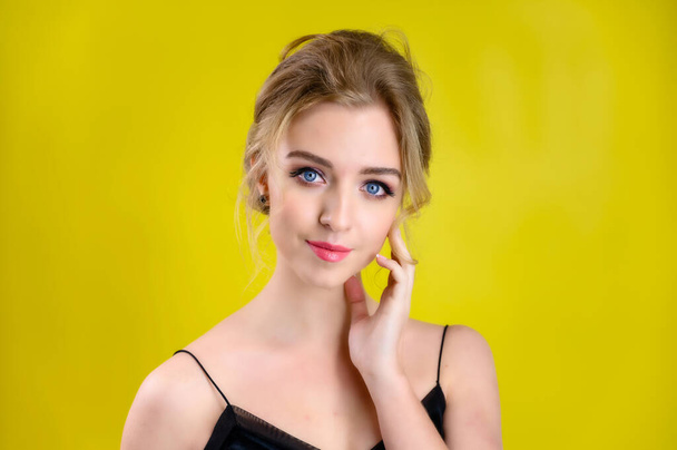 The concept of cosmetics, fashion and style. Glamorous beauty portrait of a pretty blonde model with excellent makeup and a beautiful hairstyle on a yellow background in the studio. - Foto, Imagen