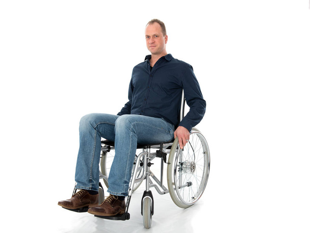 young man sitting on chair and holding a wheelchair - Fotografie, Obrázek