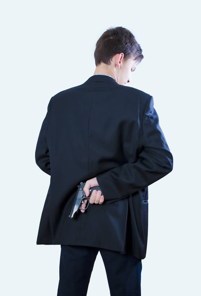 A man holding a gun on his back. The gunman held his gun behind him.Crime Concept.Criminality Concept. Back view - Foto, Imagem