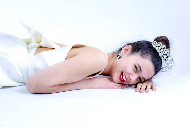 Beautiful bride lying down on the floor laughing. Isolated on white. Copy space - Fotografie, Obrázek
