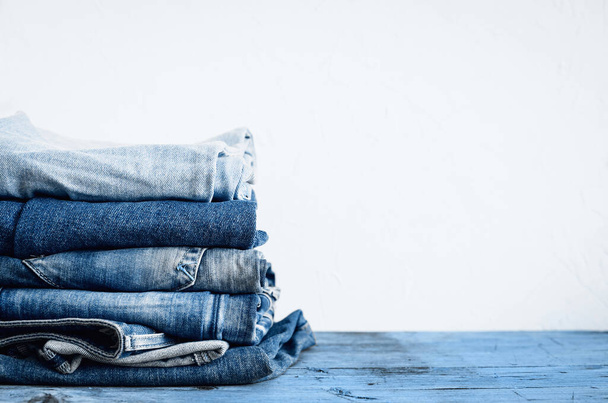 Jeans empilhados em uma mesa de madeira
 - Foto, Imagem