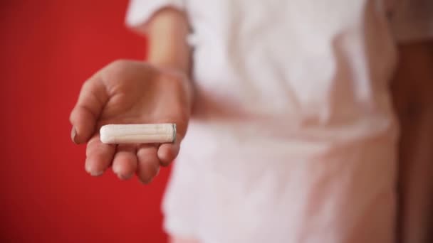 the concept of menstruation ovulation in girls girl on a red background holding a tampon gasket  - Filmmaterial, Video