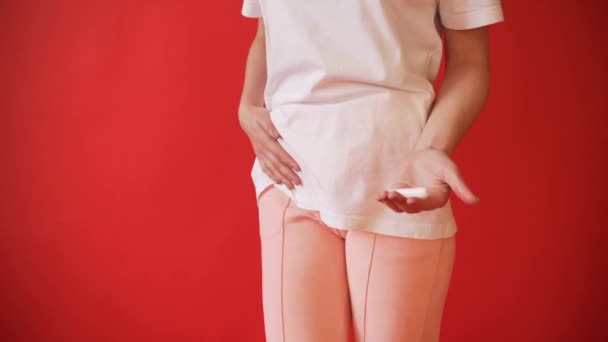 the concept of menstruation ovulation in girls girl on a red background holding a tampon gasket - Filmmaterial, Video