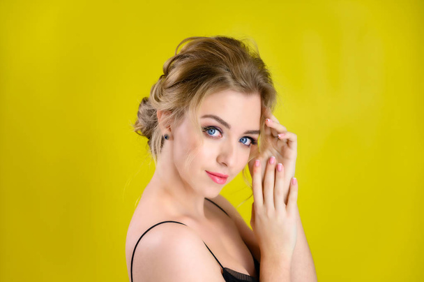 Glamorous beauty portrait side view of a pretty blonde model with excellent makeup and a beautiful hairstyle on a yellow background in the studio. The concept of cosmetics, fashion and style. - Fotoğraf, Görsel