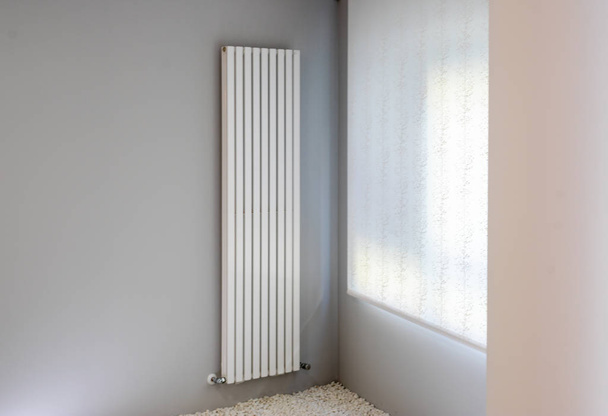 radiador blanco en la pared gris con ventana
 - Foto, imagen