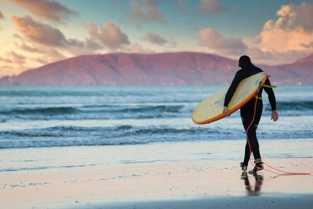 Самотній серфер заходить в океан на світанку на пляжі Пісмо. - Фото, зображення