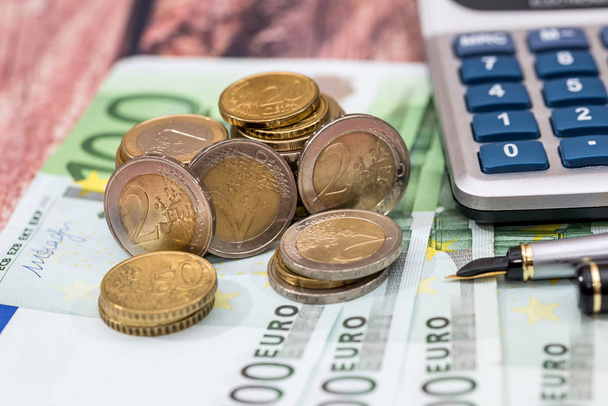 100 euro bills met inkt pen, munt en calculator. - Foto, afbeelding